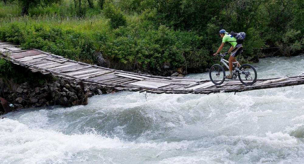 Precariously mountain biking across a wooden bridge.