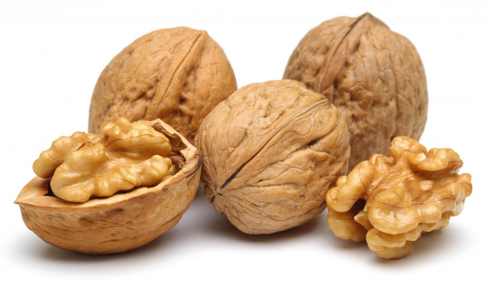 Three unshelled walnuts, one partially shelled, and one completely shelled.