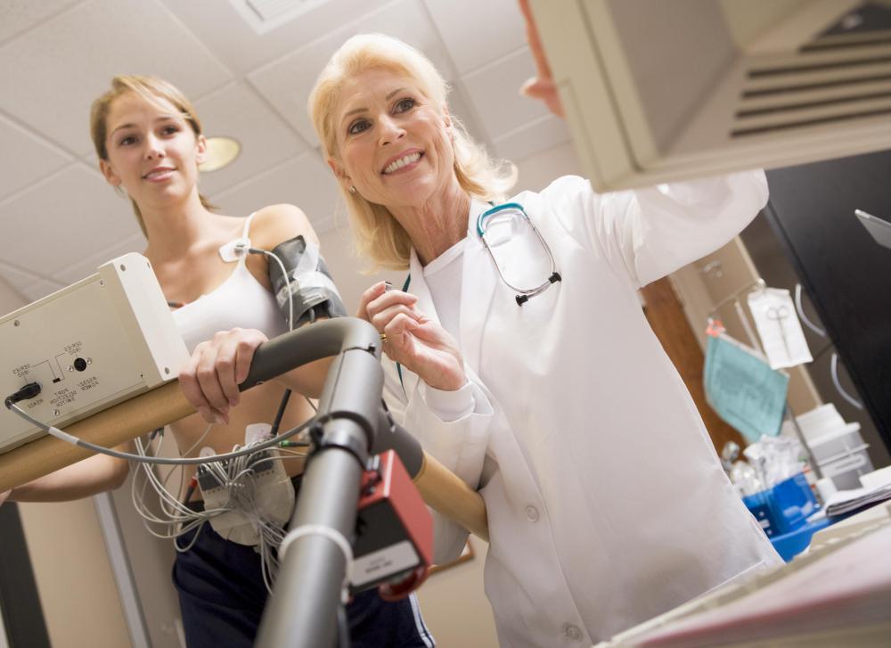 Woman on a treadmill reviewing results with her doctor.