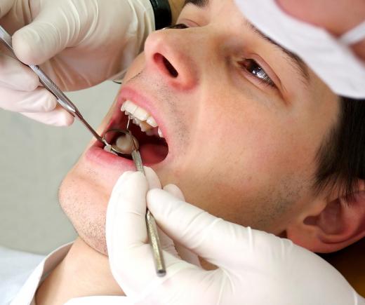 A dentist examines a patient's teeth for decalicification.