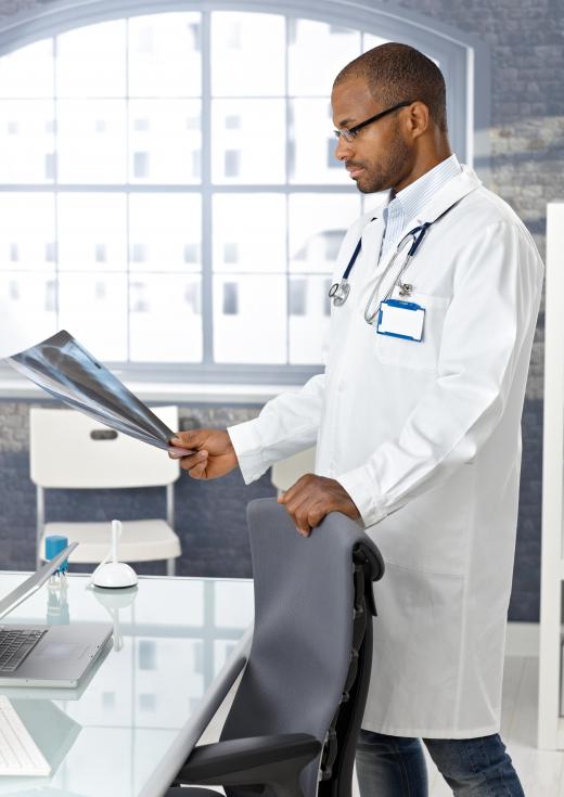 A radiologist examines a chest X-ray, a procedure that exposes the patient's cells to radiation.